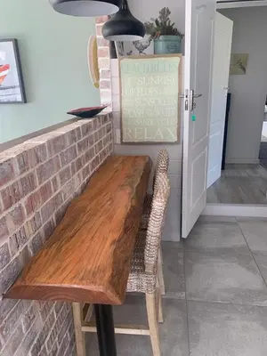 a wooden table in a kitchen with a brick wall at Just Chill Betty's Bay in Bettyʼs Bay