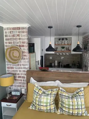 a room with a bed with two pillows and a kitchen at Just Chill Betty's Bay in Bettyʼs Bay
