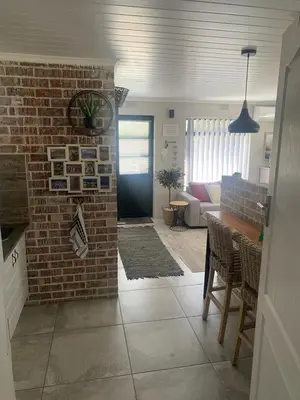 a living room with a brick wall and a door at Just Chill Betty's Bay in Bettyʼs Bay