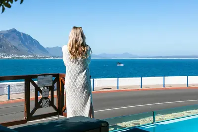 a woman standing on a bridge looking at the water at Harbour House Hotel - Manor House in Hermanus