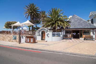 a restaurant on the side of a street with palm trees at Harbour House Hotel - Manor House in Hermanus