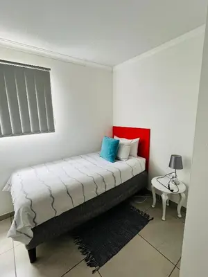 a bedroom with a bed and a table in it at Covenant Place in Cape Town