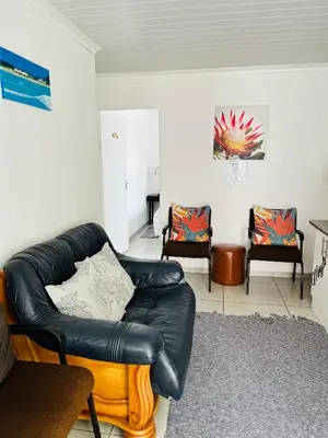 a living room with a leather couch and two chairs at Covenant Place in Cape Town