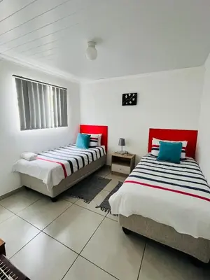two beds in a room with red and white at Covenant Place in Cape Town