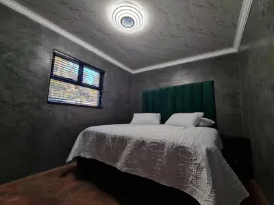 a bedroom with a bed with a green headboard and a window at Hoogeland's Wood Cabins in Eersterivier