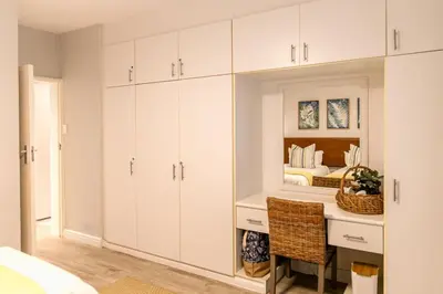 a bedroom with white cabinets and a bed at Milas Place Spacious & Comfortable at Bayview in Hermanus