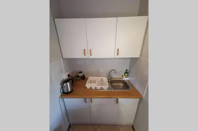 a small kitchen with white cabinets and a sink at Cozy, peaceful garden cottage in Cape Town