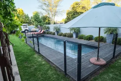a fence with an umbrella next to a swimming pool at Home in Cape Town-The Homestead in Stellenbosch