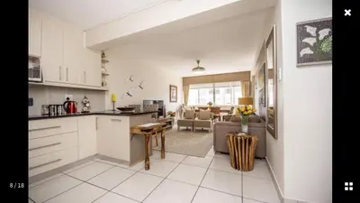 an open kitchen and living room with a couch and a table at Strand Getaways Apartment in Cape Town