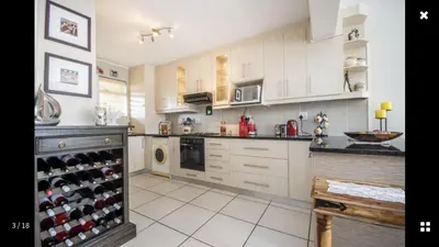 a kitchen with white cabinets and a wine cellar at Strand Getaways Apartment in Cape Town