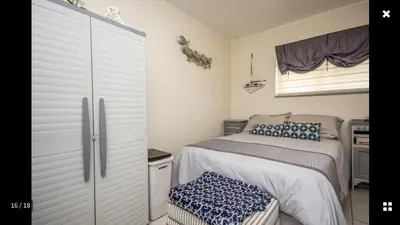a small bedroom with a bed and a dresser at Strand Getaways Apartment in Cape Town