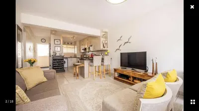 a living room with a couch and a tv at Strand Getaways Apartment in Cape Town