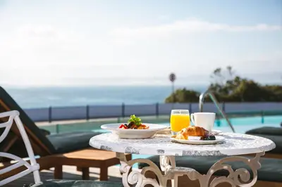 a table with a plate of food and two glasses of orange juice at Harbour House Hotel - Harbour Square in Hermanus
