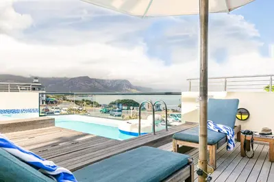 a balcony with a view of the pool and the ocean at Harbour House Hotel - Harbour Square in Hermanus