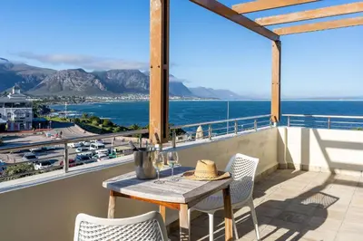 a table on a balcony with a view of the ocean at Harbour House Hotel - Harbour Square in Hermanus