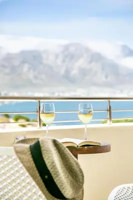 two glasses of white wine sitting on a table with a book at Harbour House Hotel - Harbour Square in Hermanus