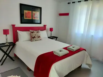 a bedroom with a large white bed with two towels on it at Cottage Amnesia in Bettyʼs Bay
