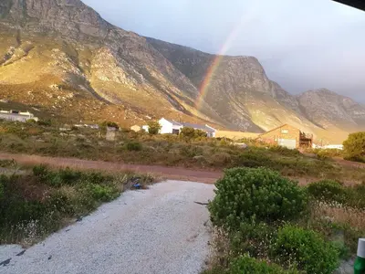 a rainbow in the mountains with a dirt road at Cottage Amnesia in Bettyʼs Bay