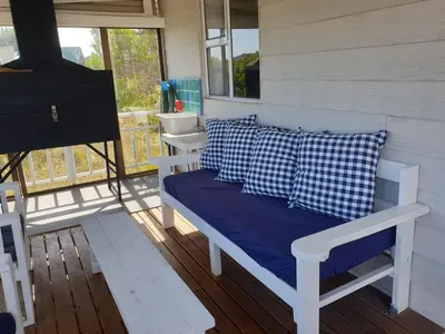 a porch with a bench and a sink in a room at Cottage Amnesia in Bettyʼs Bay