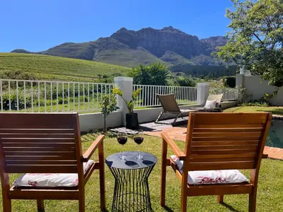two chairs and a table in a yard with mountains at House on Charme in Stellenbosch