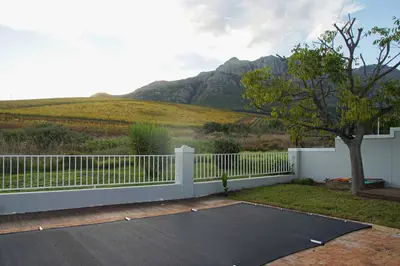 a driveway with a white fence and mountains in the background at House on Charme in Stellenbosch