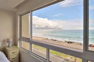a bedroom with a large window with a view of the ocean at Ocean View C403 by CTHA in Bloubergstrand