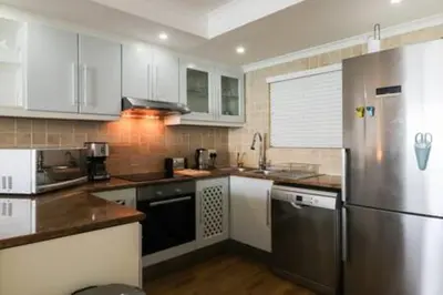 a kitchen with white cabinets and a stainless steel refrigerator at Ocean View C403 by CTHA in Bloubergstrand