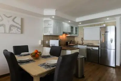 a kitchen with a table with chairs and a refrigerator at Ocean View C403 by CTHA in Bloubergstrand
