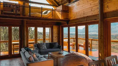 a living room with chairs and a table and windows at Stonewood Mountain Cabin in Breerivier