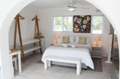 a bedroom with a large white bed and a table at 57 on Vermont in Hermanus