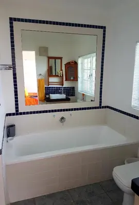 a bathroom with a white tub and a mirror at 57 on Vermont in Hermanus