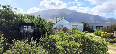a sign in front of a house with a mountain in the background at Brandys beach house bettys bay in Bettyʼs Bay