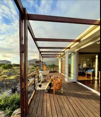 a wooden deck with a view of the ocean at Brandys beach house bettys bay in Bettyʼs Bay