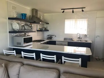 a living room with a couch and a kitchen at Hermanus Beach Club - St Tides House 19 in Hermanus