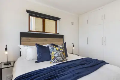 a bedroom with a bed with blue sheets and pillows at Cisterama 102 in Cape Town