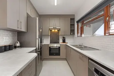 a kitchen with white cabinets and a stove top oven at Cisterama 102 in Cape Town