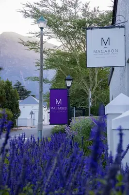 a sign for a m macaroon building with purple flowers at Macaron Boutique Guest House in Franschhoek