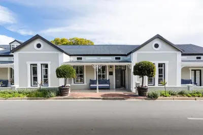 a white house with trees in front of it at Macaron Boutique Guest House in Franschhoek