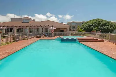 a large pool of blue water in front of a house at Luxury @ the Ocean in Hermanus