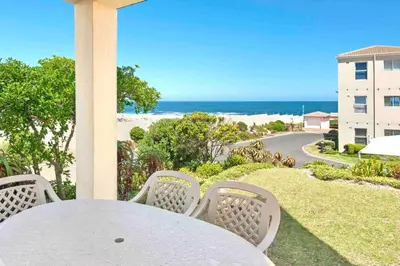 a table and chairs on a porch with a view of the ocean at Luxury @ the Ocean in Hermanus