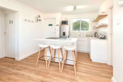 a kitchen with white cabinets and a counter with stools at Luxury @ the Ocean in Hermanus