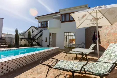 a patio with a table and chairs and an umbrella at La Maison On Main Self-Catering Villa in Paarl