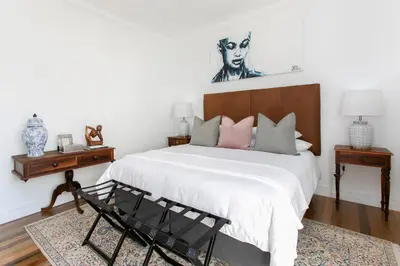 a bedroom with a large bed with white sheets and pink pillows at La Maison On Main Self-Catering Villa in Paarl