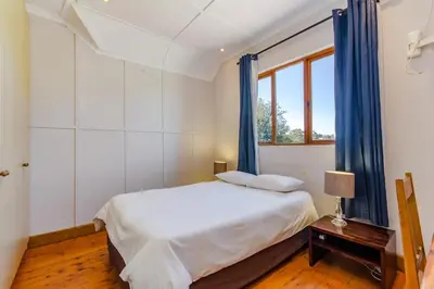 a bedroom with a bed with blue curtains and a window at the MANOR house by Kana Guest Farm - Ideal for groups in Stellenbosch