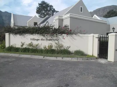 a white house with a white fence and a gate at Smith Cottage in Franschhoek