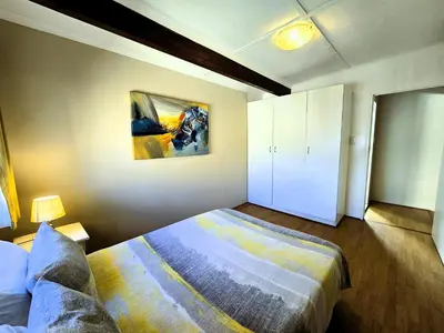 a bedroom with a bed and a painting on the wall at Walters Lane Deluxe Garden Apartment 3 - No loadshedding in Cape Town