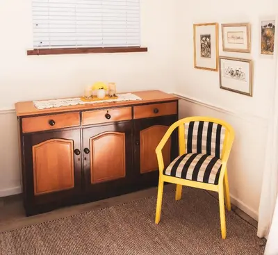 a yellow chair and a wooden cabinet in a room at Birdsong in Hermanus
