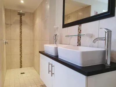 a bathroom with two sinks and a shower at Birdsong in Hermanus