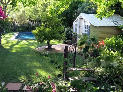 a garden with a swimming pool and a fence at Featherbed in Somerset West
