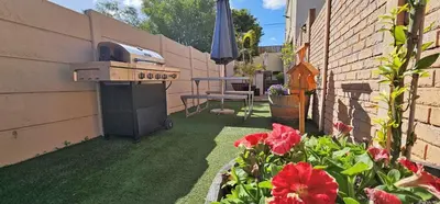 a backyard with a grill and a table and flowers at Walters Lane Comfort Apartment 2 - No Loadshedding in Cape Town
